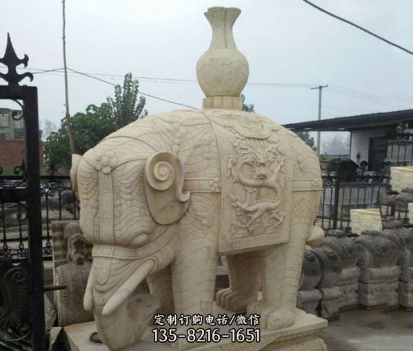 这是一尊位于别墅小区的大象雕塑，它背负着一个花瓶，…