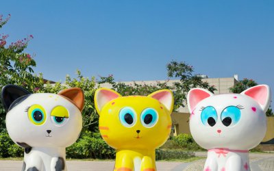 玻璃钢卡通猫雕塑位于公园街道，由三只小猫坐成一座圆…