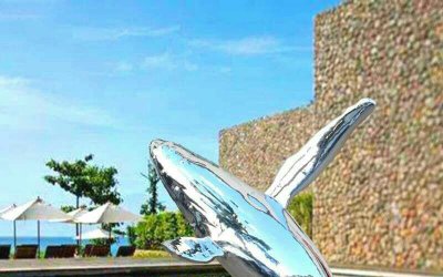 公园里摆放的跳跃的玻璃钢创意鲸鱼雕塑，是一个色彩艳…