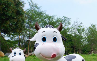 这座可爱的牛雕塑位于一个壮丽的牧场中，两只卡通呆萌…