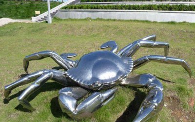 草地上摆放的不锈钢创意螃蟹雕塑，是一件来自艺术家的…